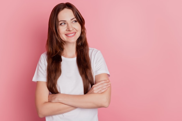 Portrait of interested inspired girl folded arms look empty space toothy smile on pink background