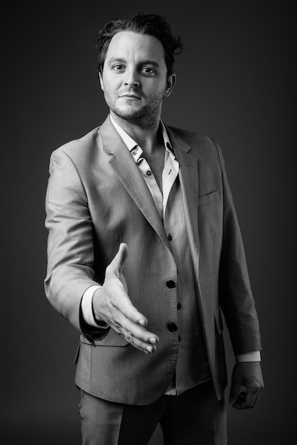 Portrait of Italian businessman wearing suit on gray in black and white