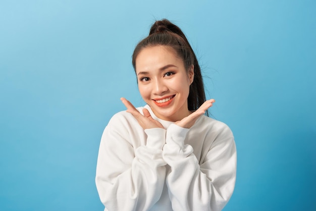 Portrait of joyful carefree adorable adult woman smiling broadly and holding palms near cheeks being playful and emotive with positive attitude to life