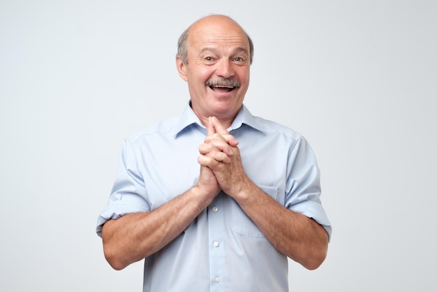 Portrait of joyful handsome mature man clapd palms waits to hear something pleasant recieves compliments