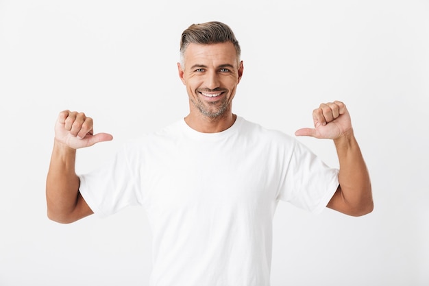 Photo portrait of joyful man 30s with bristle wearing casual t-shirt pointing fingers at himself isolated on white