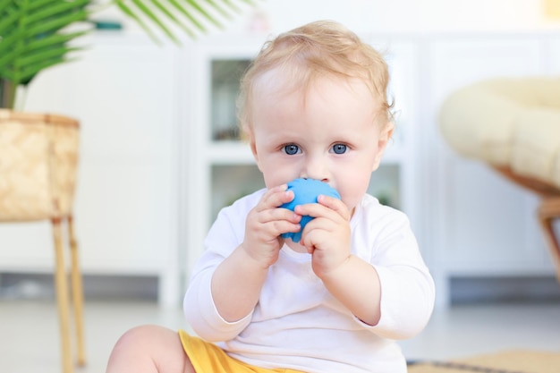 Portrait kid chewing on a toy for teeth sitting