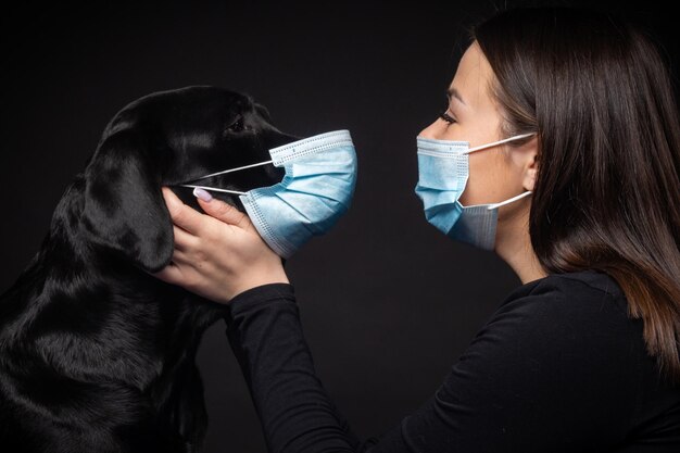 Portrait of a Labrador Retriever dog in a protective medical mask with a female owner