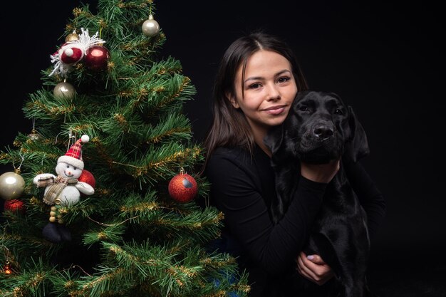 Portrait of a Labrador Retriever dog with its owner near the new year's green tree