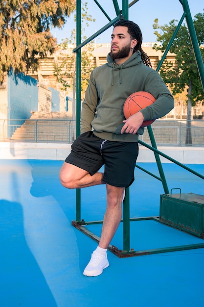 Portrait of a Latin Afro man posing with a ball on a basketball court