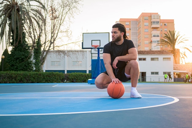 Portrait of a Latin Afro man posing with a ball on a basketball court