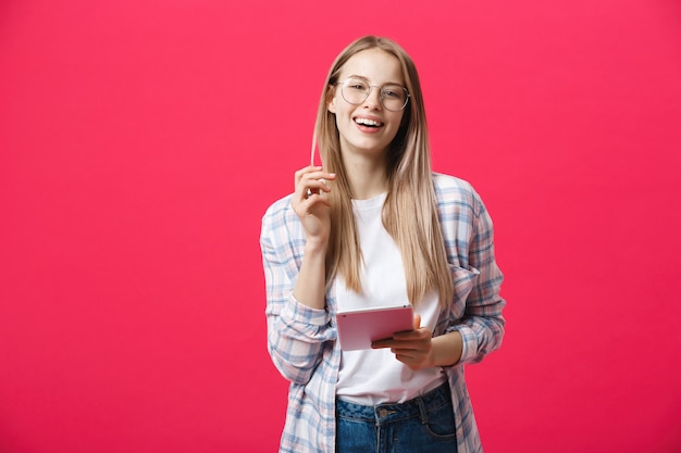 Portrait of a laughing woman using tablet computer isolated on a pink background and looking at camera