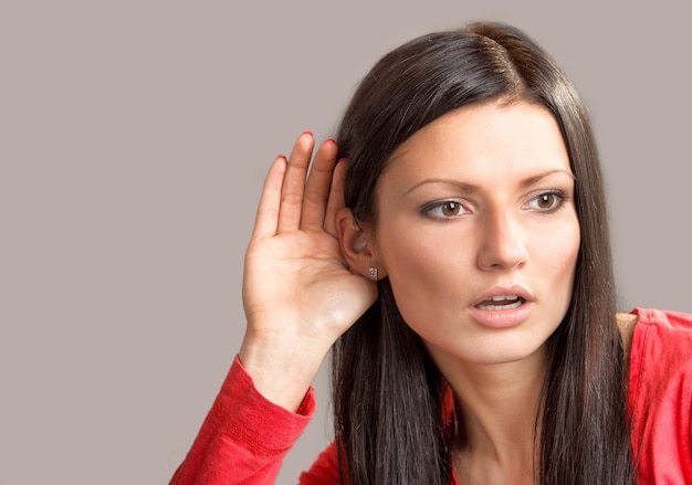 Portrait of a listening girl on gray background