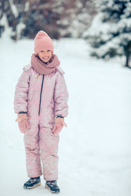 Portrait of little adorable girl in snow sunny winter day