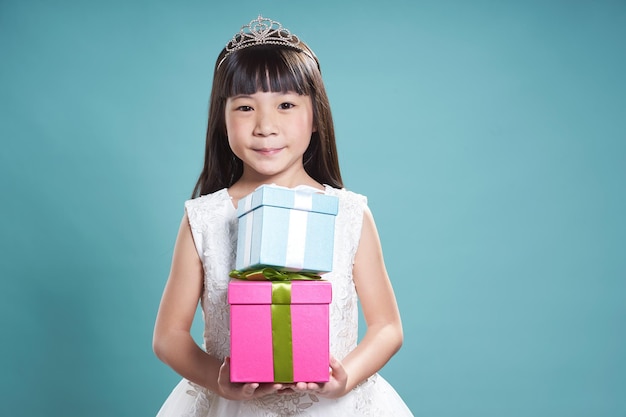 Portrait of little asian beautiful girl holding two present box on vintage blue background