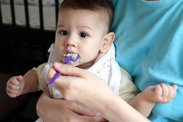 Portrait of little baby boy eating food Baby with a spoon in feeding chair Cute baby eating first meal