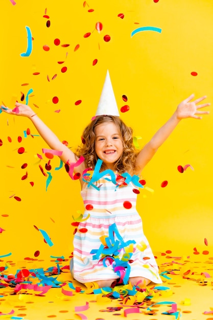 Portrait of a little beautiful girl celebrating her birthday. 
 colorful confetti. 