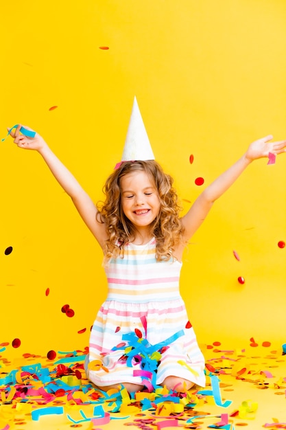 Portrait of a little beautiful girl celebrating her birthday. 
 colorful confetti. 