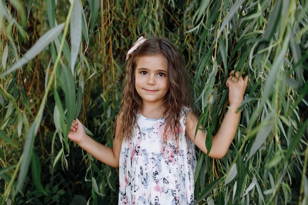 Portrait of a little beautiful little girl on nature on summer day. The playing in the park with parents. Close Up.