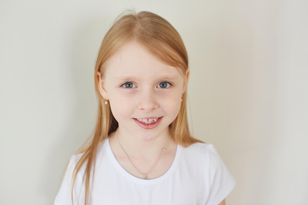 Portrait of little blonde girl on white background in white t-shirt