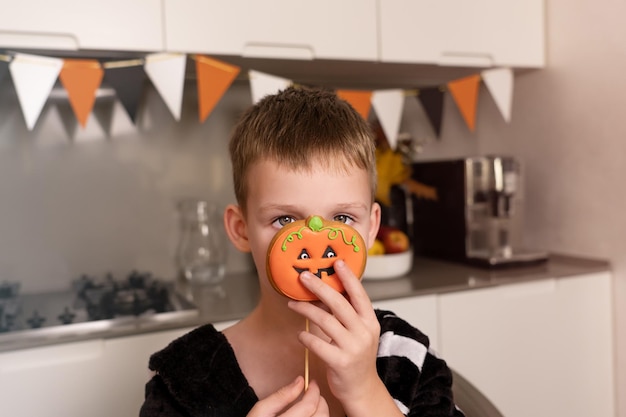 Portrait of a little boy on a black background with halloween gingerbread