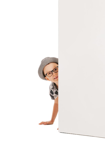 Portrait of little boy child peeking out the corner playing isolated over white studio background