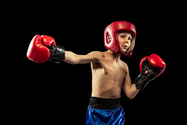 Portrait of little boy child training boxing isolated over black studio background Little sportsman