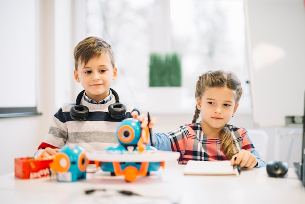 Portrait of a little boy looking at girl playing with robotic toy