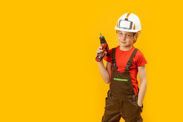 Portrait of little boy pretends to drill wall with drill yellow isolated background Boy teenager as builder worker Copy space mockup