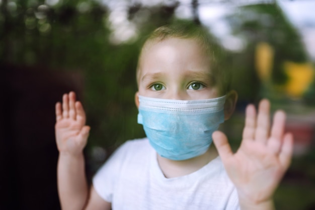 Portrait of little boy with medical face mask looking at camera in the city