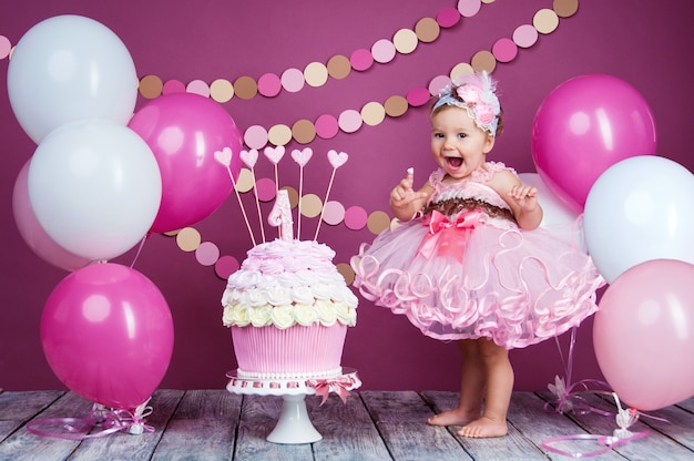 Portrait of a little cheerful birthday girl with the first cake. Eating the first cake. Smash cake.