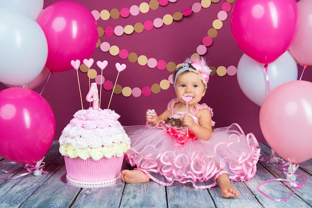 Portrait of a little cheerful birthday girl with the first cake