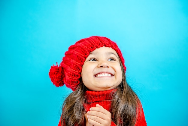 portrait of a little curlyhaired girl in a knitted red hat in winter little girl with dark hair