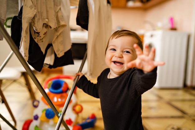 Portrait of little cute boy in home interior drying clothes help with housework