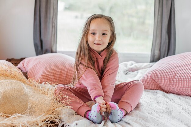 Portrait of a little cute girl sitting by the window in a tourist trailer