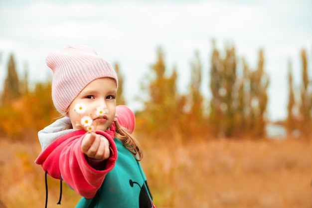 portrait of a little girl on an autumn walk with a wild flower