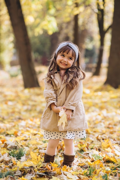 portrait little girl in a beige coat walks in the autumn park