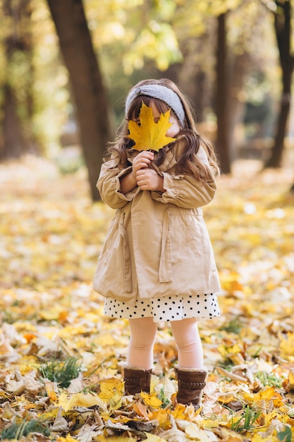 portrait little girl in a beige coat walks in the autumn park