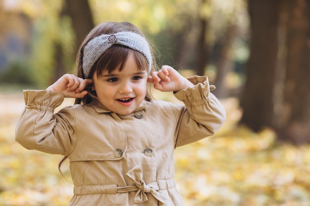 portrait little girl in a beige coat walks in the autumn park