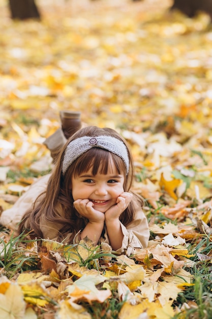 portrait little girl in a beige coat walks in the autumn park