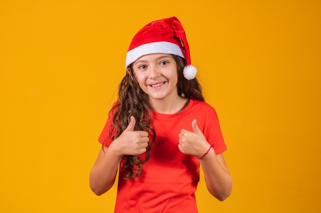 Portrait of a little girl dressed in Christmas outfit with her thumb up.