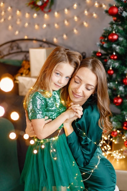 Portrait of a little girl and her mother hugging at Christmas atmosphere