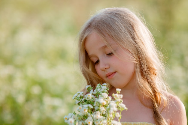 portrait  little girl holding a bouquet of flowers in a field in summer