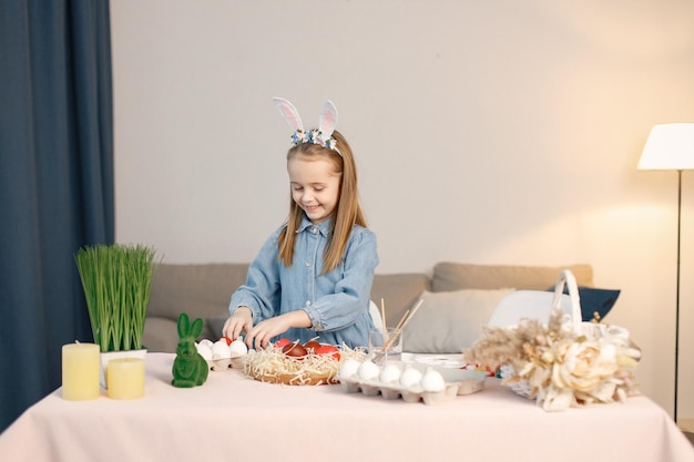 Portrait of little girl standing in modern light kitchen with Easter eggs