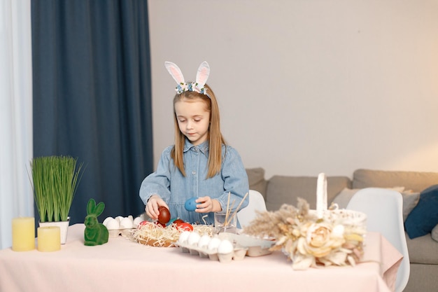 Portrait of little girl standing in modern light kitchen with Easter eggs