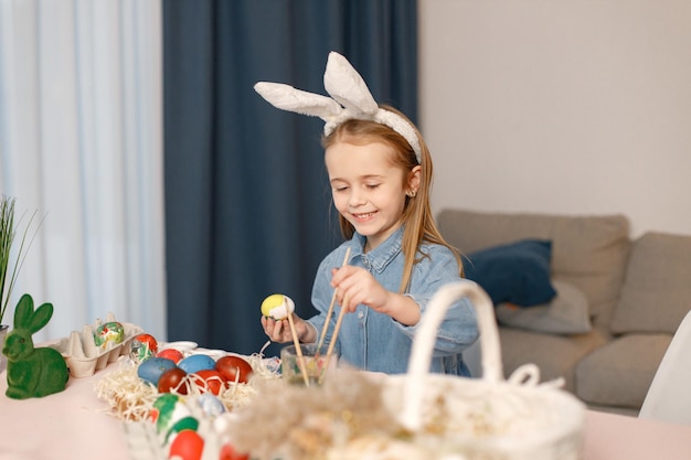 Portrait of little girl standing in modern light kitchen with Easter eggs