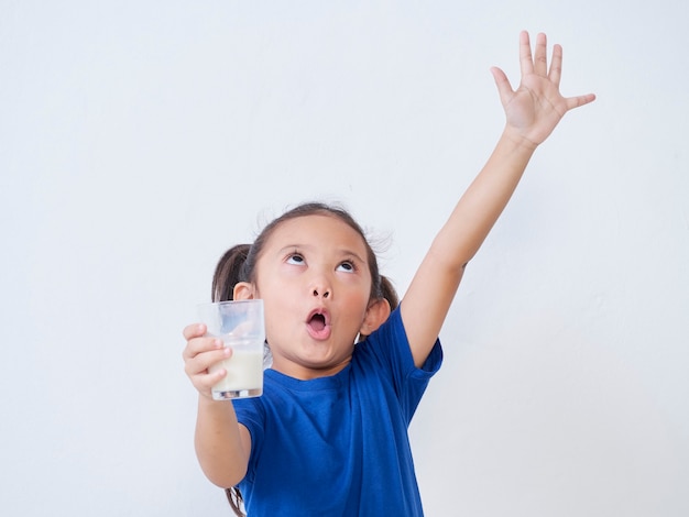 Portrait of little girl with glass of milk on light