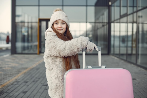 Portrait of a little girl with luggage going to airport terminal