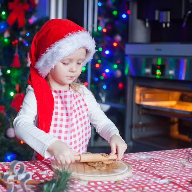 Portrait of little girl with rolling pin baking Christmas gingerbread cookies