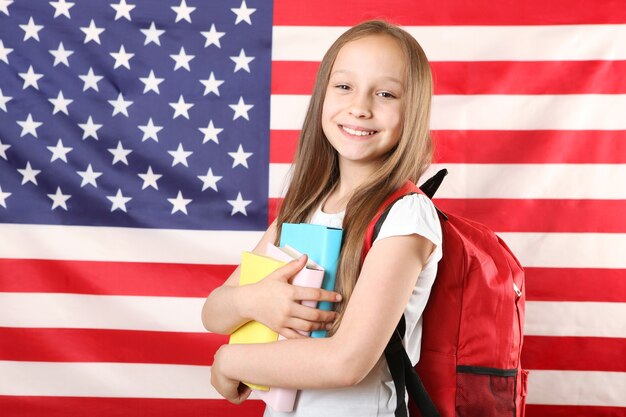 Portrait of a little girl with a school backpack and flag of america