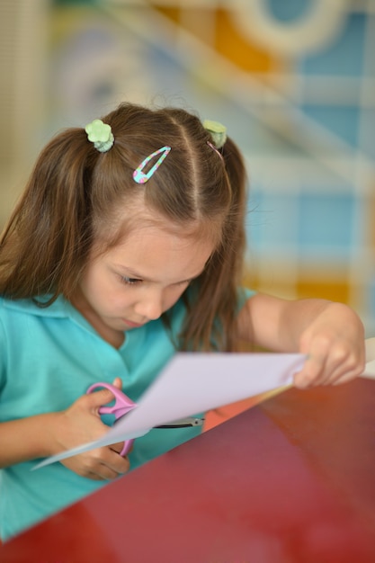 Portrait of a little girl with scissors cuts paper