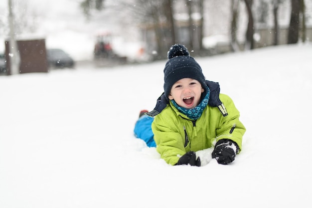 Portrait of Little Happy Boy Lies in Snow