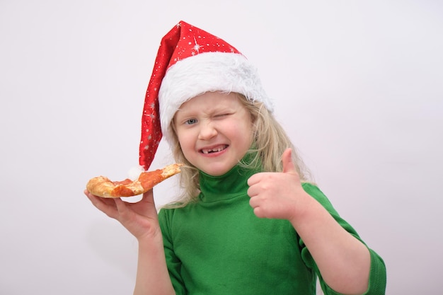 Portrait of little happy girl with santa hat eating pizza on white background