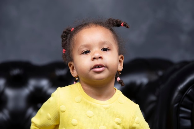 Portrait of a little playful African American girl on a dark background.