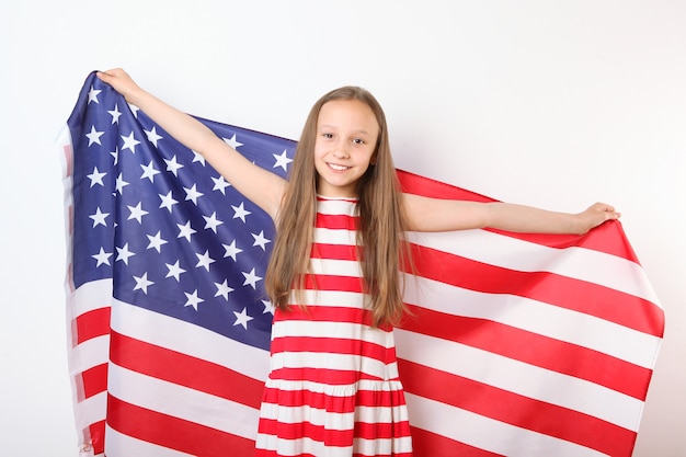 Portrait of a little positive girl with an american flag in her hands